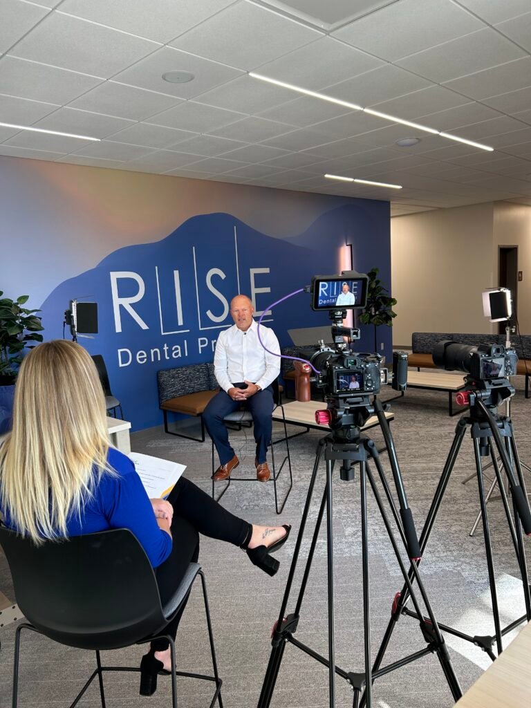 A videographer filming a professional testimonial interview for Rise Dental, featuring a two-camera setup and lighting to capture high-quality content for BLC Community.